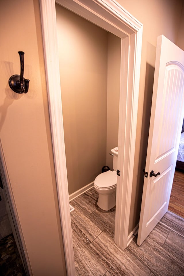 bathroom with toilet, baseboards, and wood finished floors