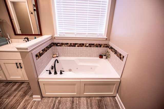 full bath featuring a tub with jets, wood finished floors, and vanity