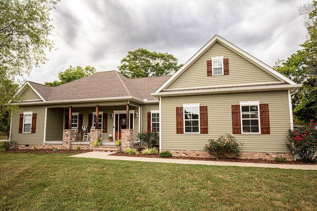 view of front of property with a front yard, crawl space, covered porch, and roof with shingles