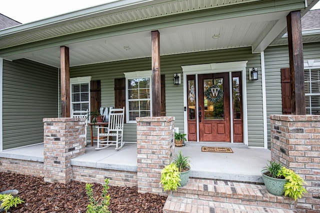 property entrance with covered porch and brick siding