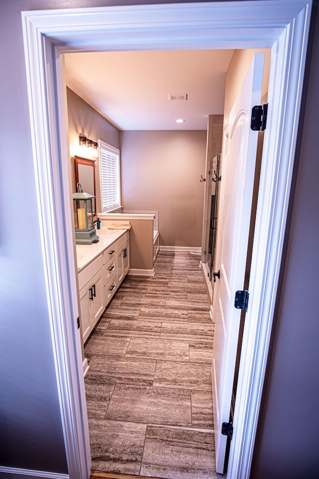 full bathroom featuring vanity, wood finished floors, a shower stall, and visible vents