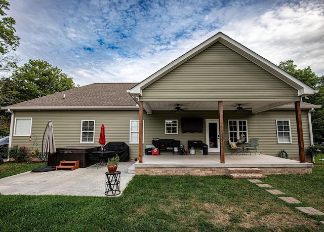 back of house featuring a yard, a patio area, a ceiling fan, and a hot tub