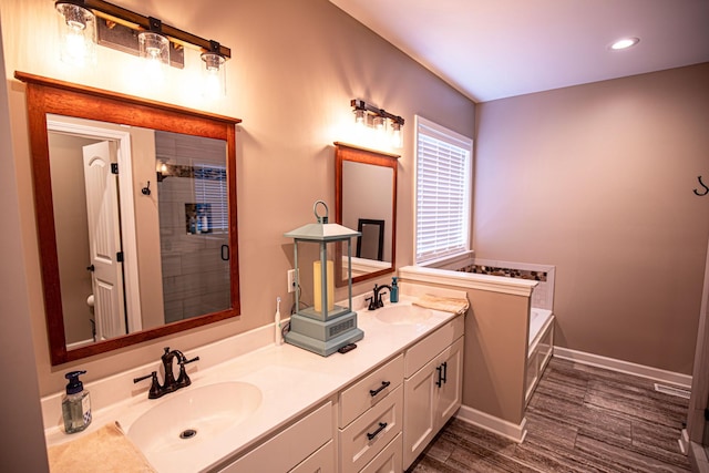 full bathroom featuring a stall shower, double vanity, a sink, and wood finished floors