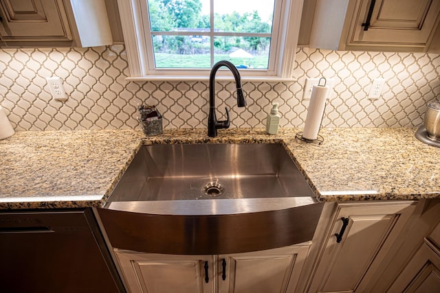 kitchen featuring dishwasher, tasteful backsplash, a sink, and light stone counters