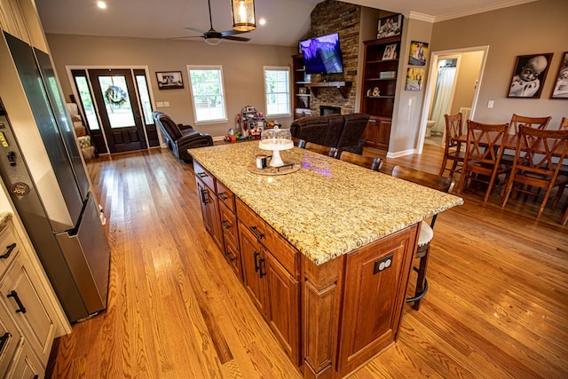 kitchen with light wood-style flooring, light stone counters, open floor plan, refrigerator, and a fireplace