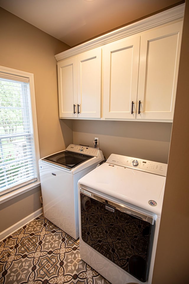 clothes washing area featuring cabinet space, washing machine and dryer, light tile patterned floors, and baseboards