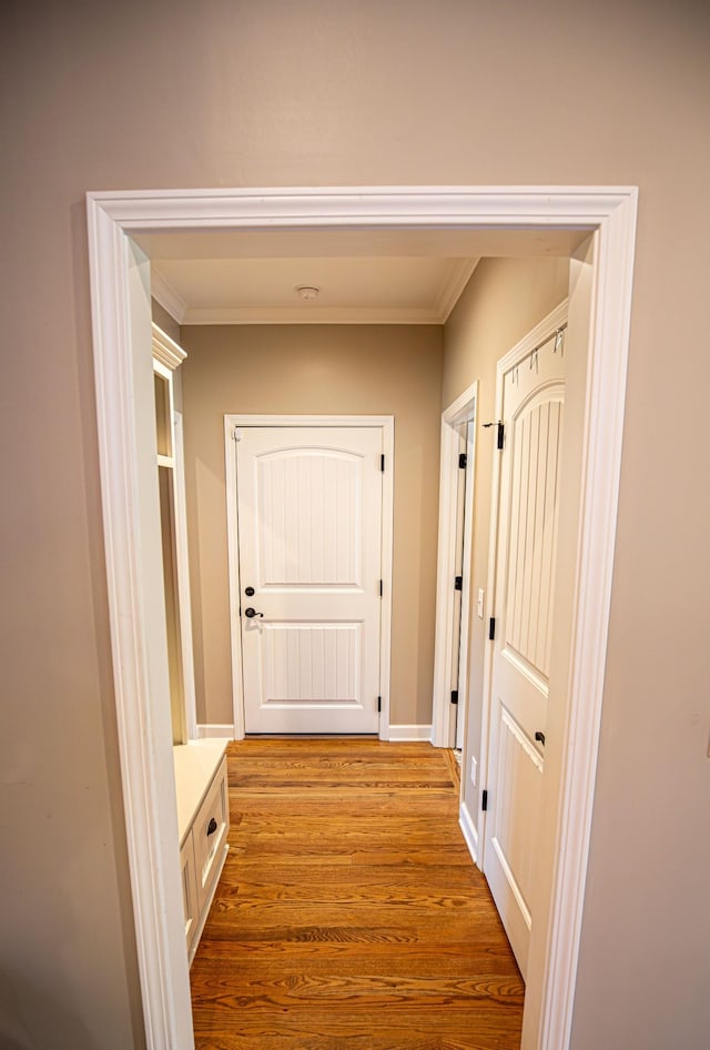 corridor with crown molding, baseboards, and wood finished floors