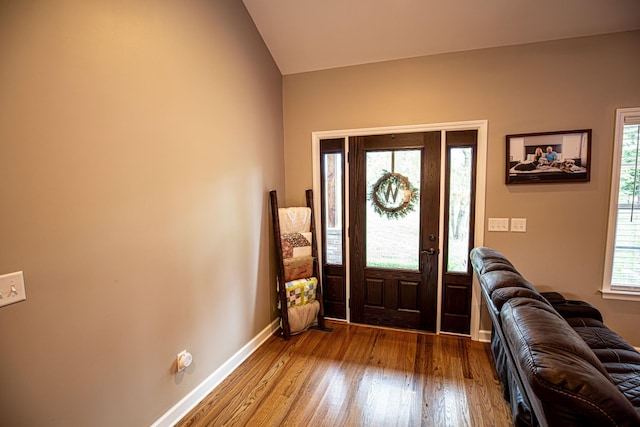 entryway featuring wood-type flooring, baseboards, and vaulted ceiling