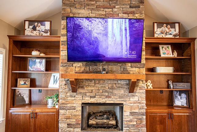 living room with lofted ceiling and a stone fireplace