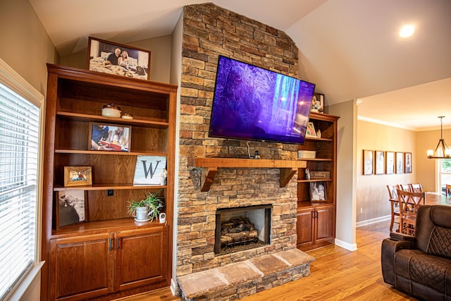 living room featuring a fireplace, lofted ceiling, an inviting chandelier, light wood-style floors, and baseboards