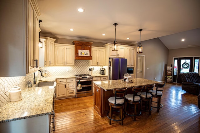 kitchen featuring range with two ovens, a center island, freestanding refrigerator, a kitchen bar, and a sink