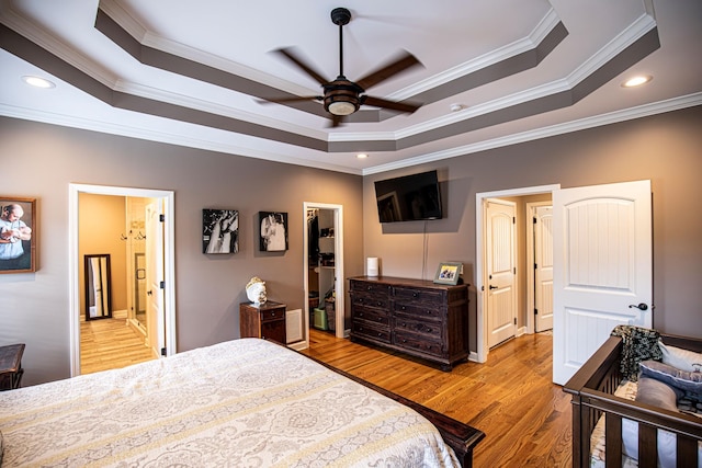 bedroom with recessed lighting, a raised ceiling, a spacious closet, light wood-style floors, and ornamental molding