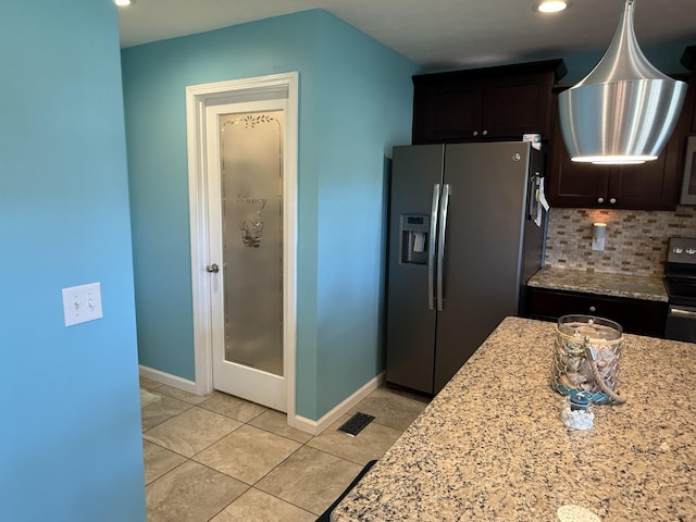 kitchen with baseboards, visible vents, decorative backsplash, light stone counters, and stainless steel refrigerator with ice dispenser