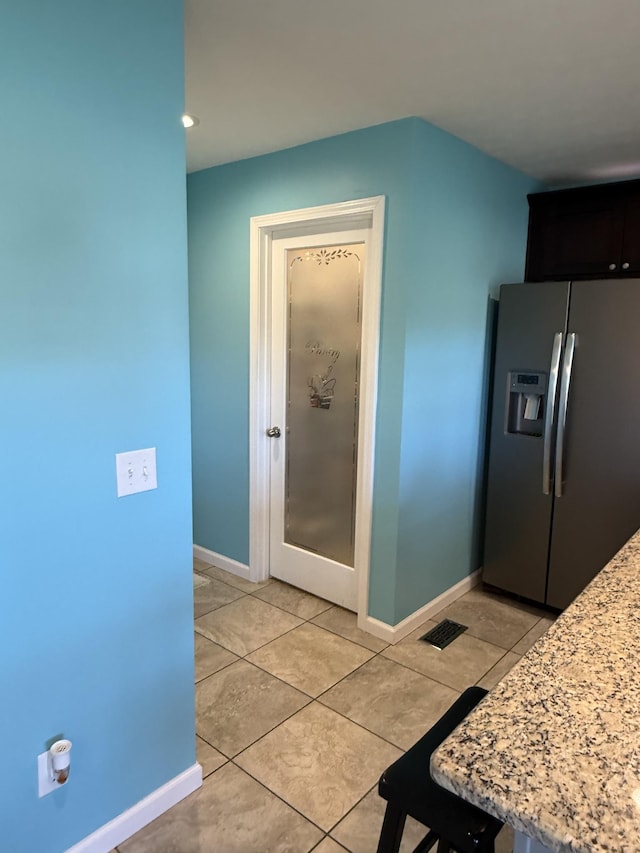 kitchen featuring baseboards, visible vents, stainless steel fridge with ice dispenser, and light tile patterned floors