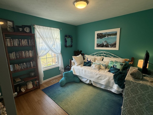 bedroom featuring a textured ceiling, visible vents, and wood finished floors