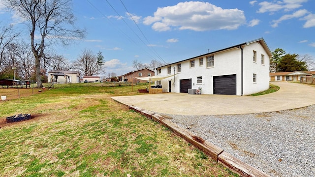 back of house featuring driveway, a garage, central AC, and a yard