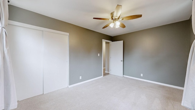 unfurnished bedroom featuring ceiling fan, baseboards, a closet, and light colored carpet