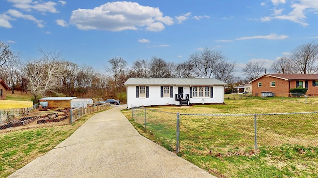 view of front facade with a fenced front yard, an outbuilding, metal roof, and a front lawn