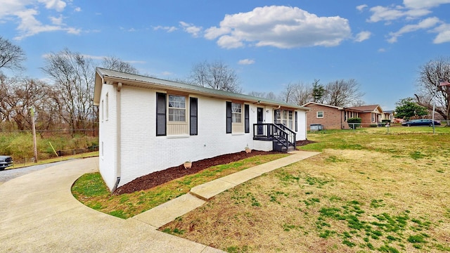 view of front facade with metal roof, brick siding, a front lawn, and concrete driveway