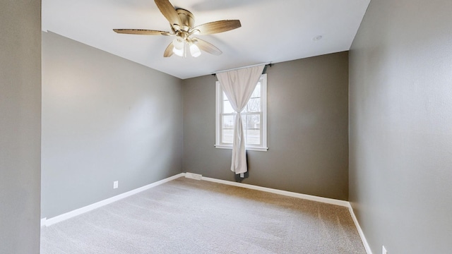 carpeted spare room featuring ceiling fan and baseboards