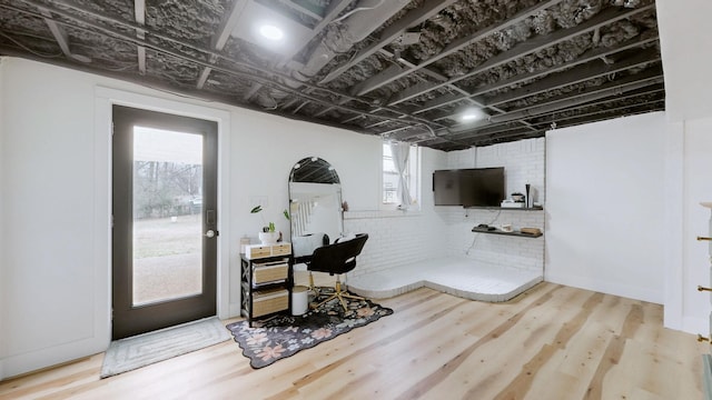 office area featuring brick wall, plenty of natural light, and wood finished floors