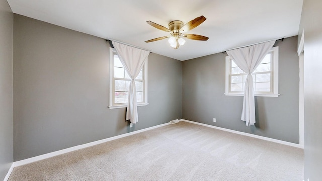 empty room featuring ceiling fan, carpet floors, visible vents, and baseboards