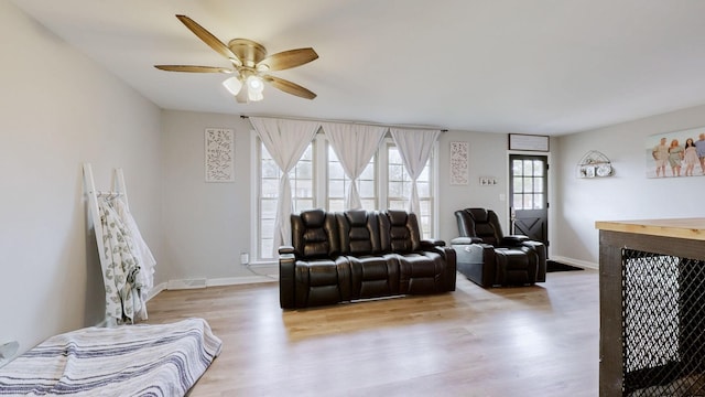 living room featuring a ceiling fan, baseboards, and wood finished floors