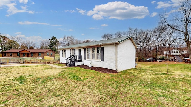 view of front facade featuring metal roof, brick siding, a front yard, and fence