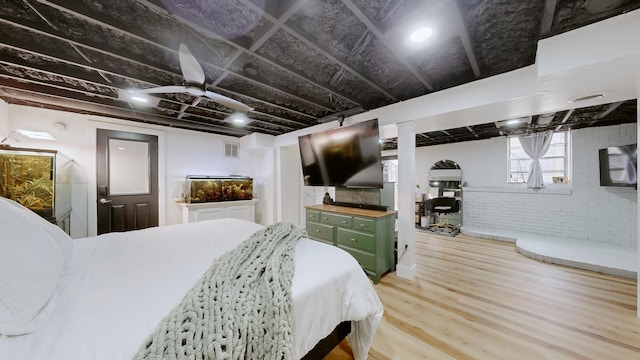 bedroom with brick wall, wood finished floors, and visible vents