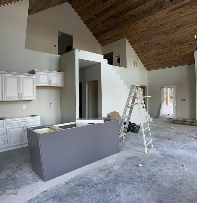 kitchen with high vaulted ceiling, a kitchen island, wood ceiling, and white cabinets