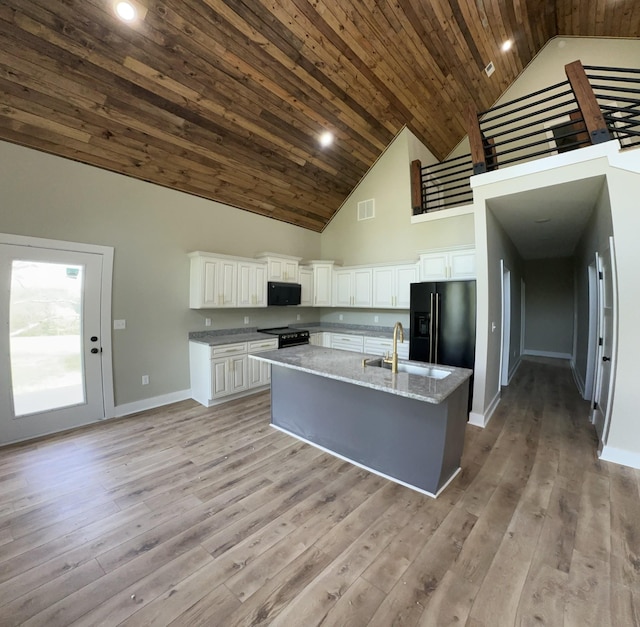 kitchen featuring visible vents, a sink, baseboards, black appliances, and high vaulted ceiling