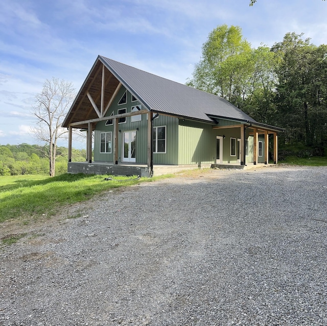 view of front of house featuring gravel driveway, a porch, and metal roof