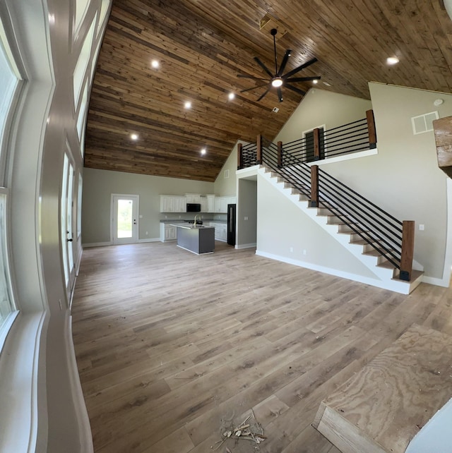 unfurnished living room featuring visible vents, a ceiling fan, baseboards, wood ceiling, and high vaulted ceiling