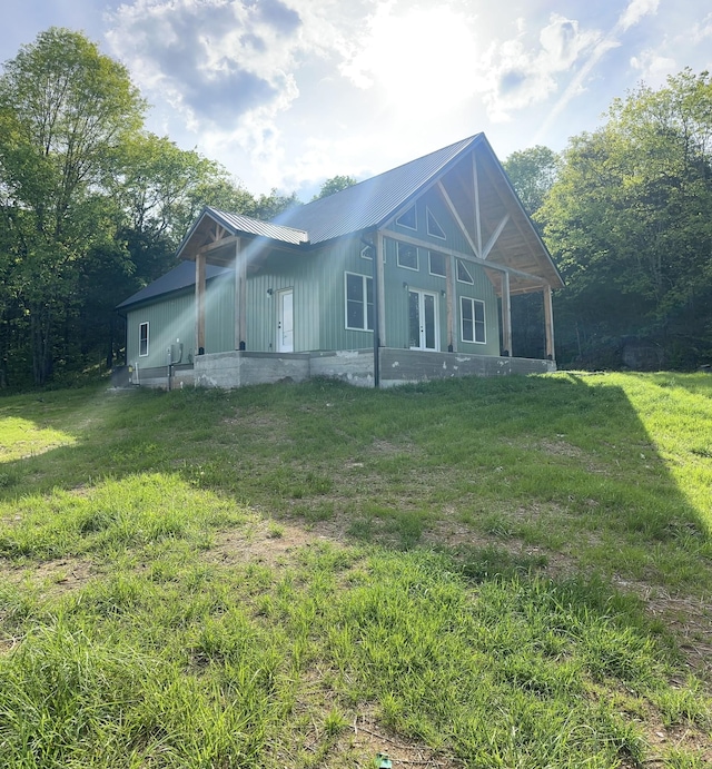 view of side of home with board and batten siding, a lawn, french doors, and metal roof
