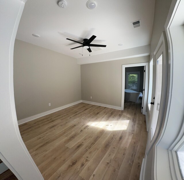 empty room featuring ceiling fan, baseboards, visible vents, and light wood-type flooring