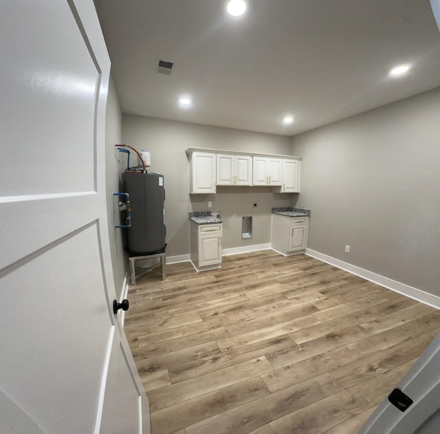 interior space featuring water heater, light wood-type flooring, visible vents, and baseboards
