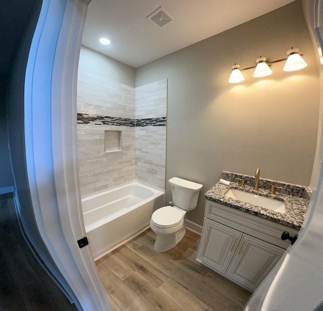 full bathroom with wood finished floors, vanity, baseboards, toilet, and visible vents