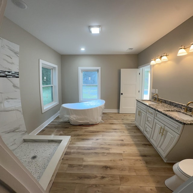 full bath featuring a freestanding bath, toilet, a sink, and double vanity