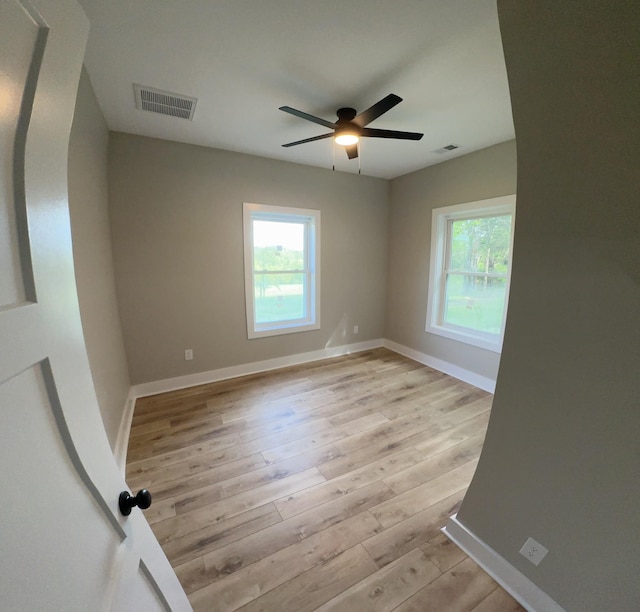 unfurnished room with visible vents, a ceiling fan, and a wealth of natural light