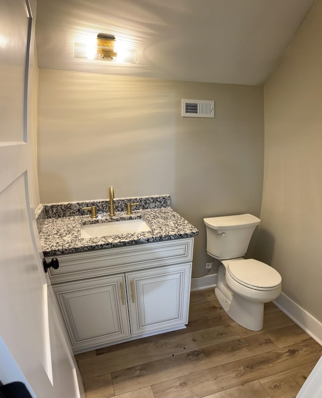 bathroom featuring wood finished floors, visible vents, toilet, vanity, and baseboards