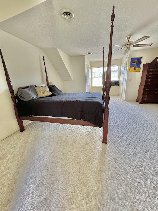 carpeted bedroom with visible vents, a textured ceiling, and a ceiling fan