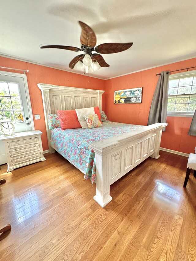 bedroom with baseboards, wood-type flooring, ornamental molding, and a ceiling fan