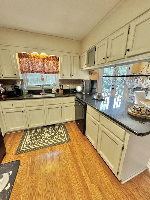 kitchen with a sink, light wood-style floors, dishwasher, and a peninsula