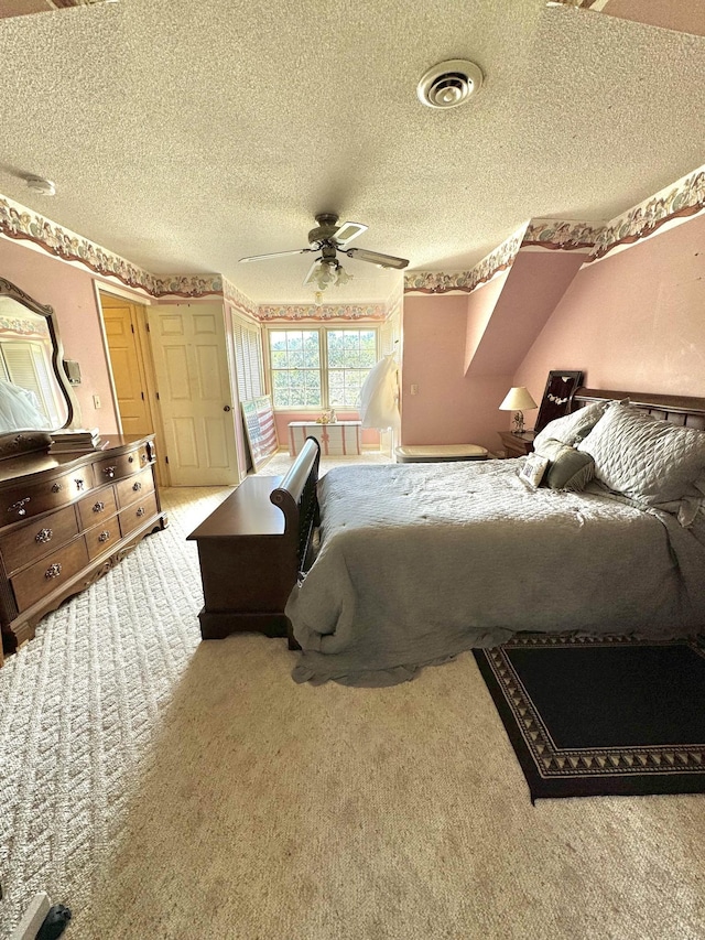 bedroom with a ceiling fan, visible vents, carpet floors, and a textured ceiling