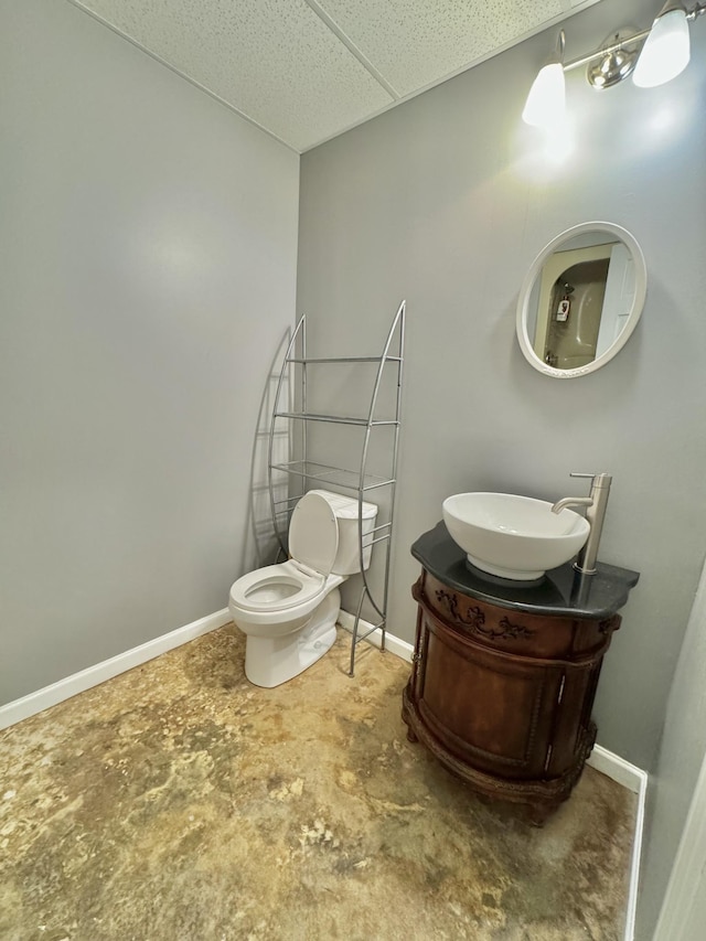 bathroom featuring toilet, baseboards, and a drop ceiling