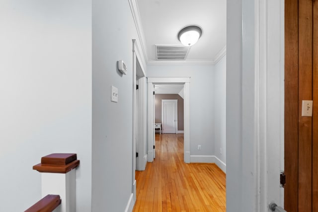 corridor featuring crown molding, baseboards, visible vents, and light wood-type flooring