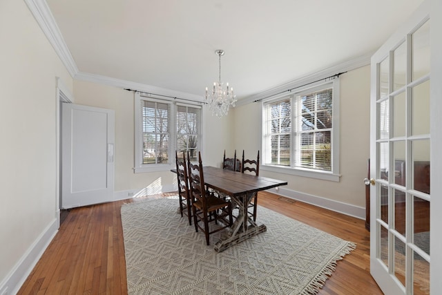 dining space with a chandelier, wood finished floors, baseboards, and ornamental molding