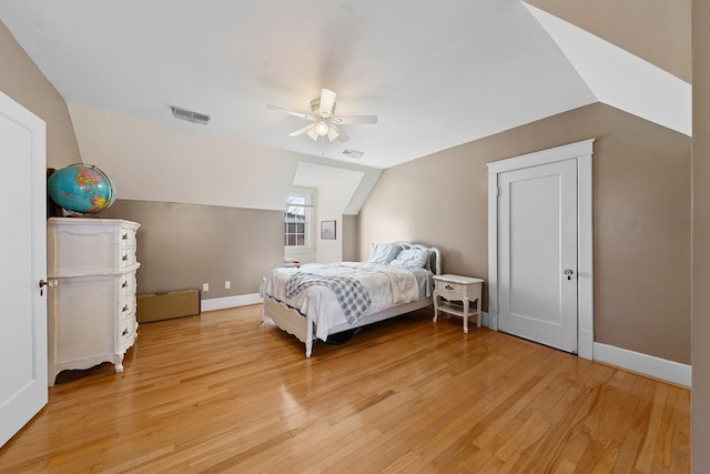 bedroom featuring visible vents, baseboards, lofted ceiling, and light wood-style floors