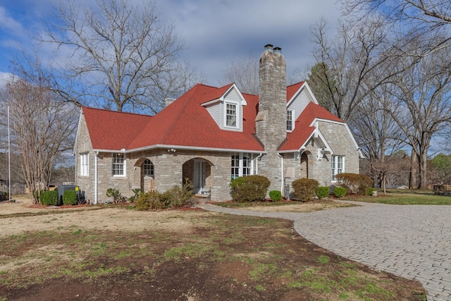 view of front facade with stone siding and a chimney