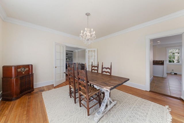 dining room featuring an inviting chandelier, light wood-style floors, baseboards, and ornamental molding